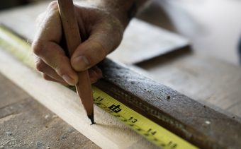 Carpenter using pencil and measurement tape on wood