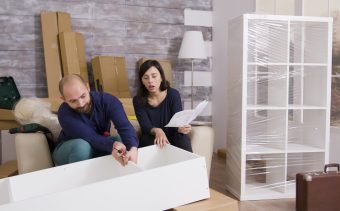 Couple smiling while assembling a shelf as a team and reading instructions.